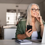Eine Frau mit einer Gleitsichtbrille und einem Smartphone