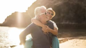 Zwei Senioren schützen Ihre Augen mit Sonnenbrillen vor der grellen Sonne am Strand